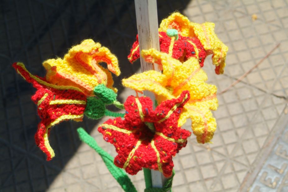 Crocheted lilies surround a tent pole at a yarn-bombing intervention in Barrio Italia. 
