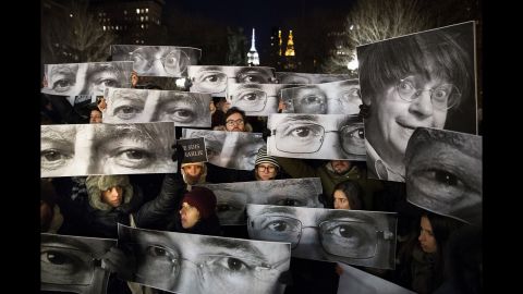 Mourners hold signs depicting victims' eyes during a rally in New York on Wednesday, January 7.