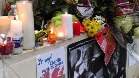 People leave tributes and lay flowers at a vigil site in Paris.
