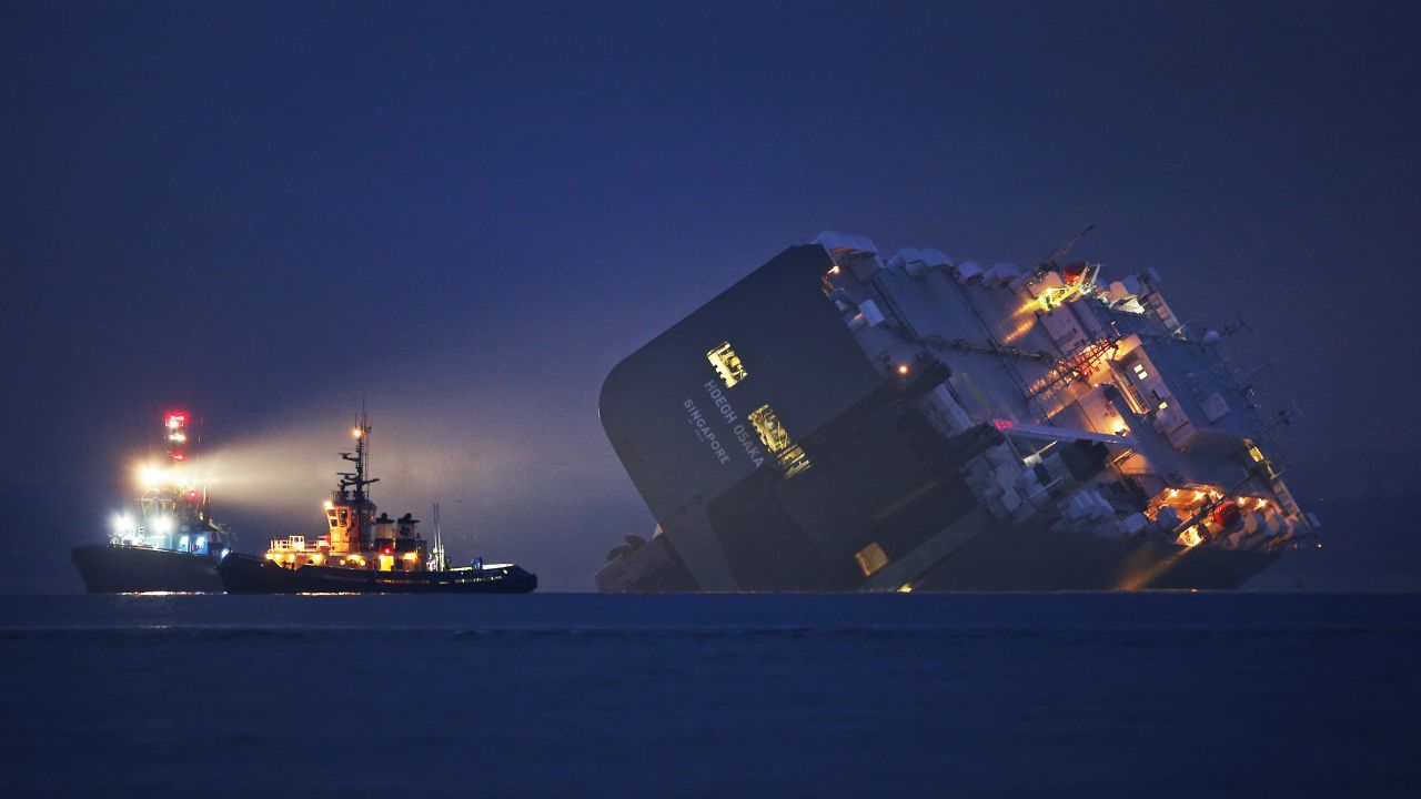 A tugboat lights the hull of the Hoegh Osaka cargo ship on Sunday, January 4. The cargo ship ran aground in the Solent, a strait near southern England. All 25 crew members were rescued overnight.