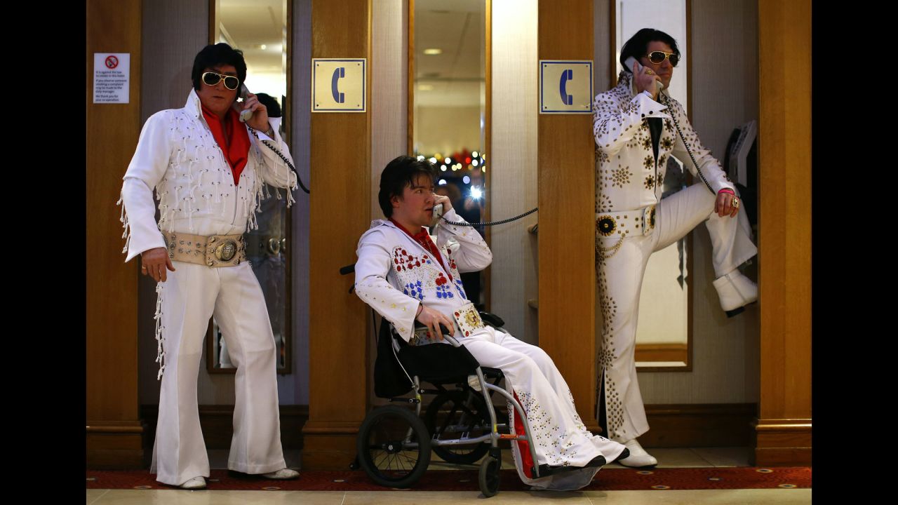 From left, Elvis Presley impersonators Phil Bailey, John Hindle and Eren Emir pose in telephone booths Friday, January 2, during an annual Elvis convention in Birmingham, England.