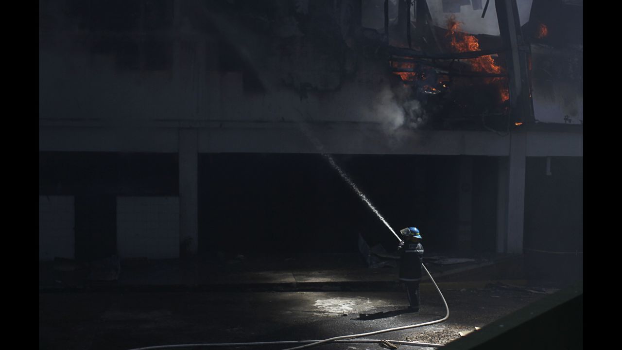 A firefighter sprays water at a shopping mall that was partially damaged Saturday, January 3, in Antiguo Cuscatlan, El Salvador.