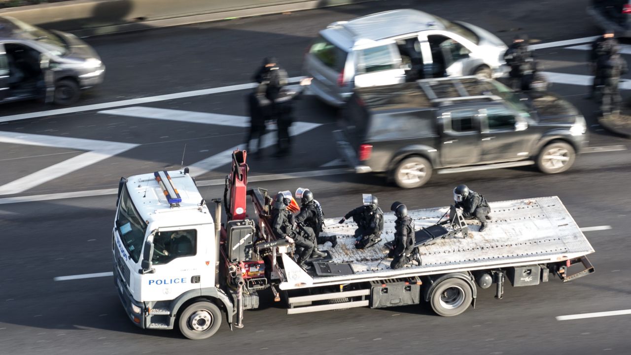 Police ride on a truck bed near the grocery store.
