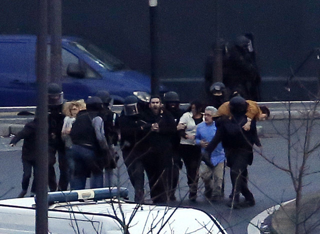 French police escort hostages away from the grocery store. At least 10 hostages managed to escape, according to a Paris police union spokesman.