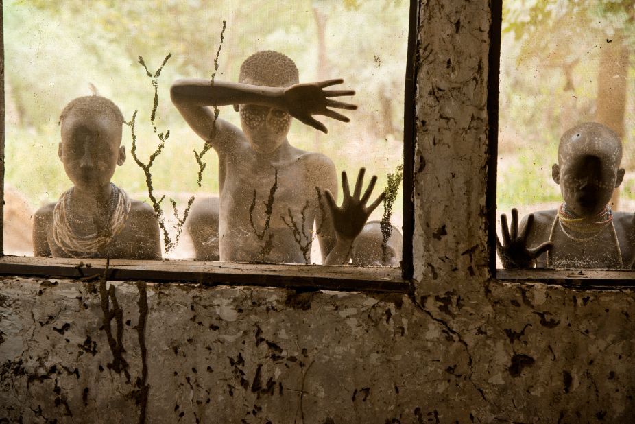 Children from Kara tribe look through screened windows.
