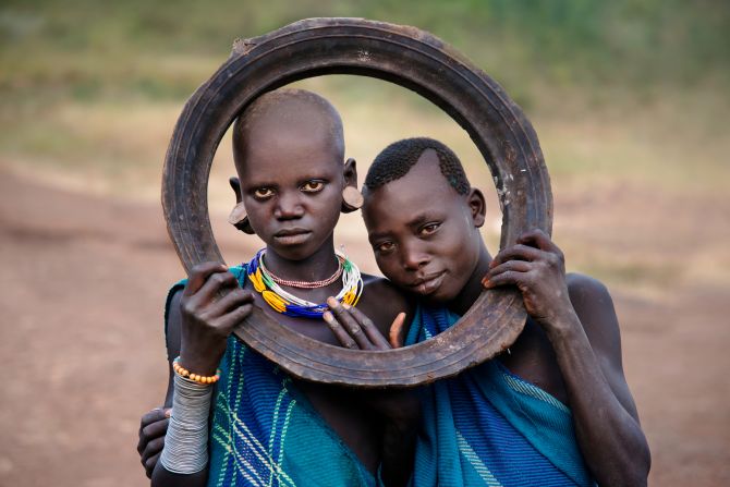 Two girls holding a tattered tire.