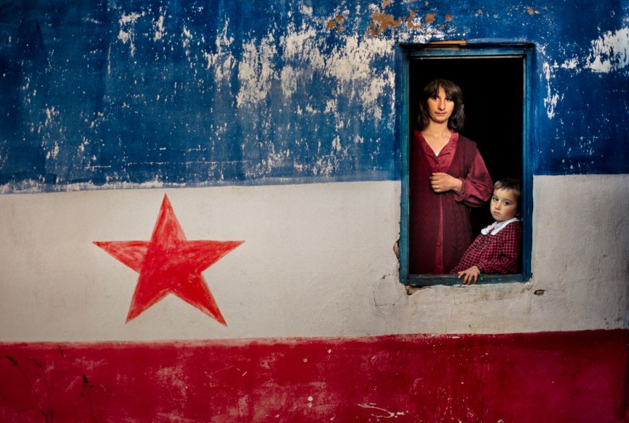 A mother and daughter stand in the window of a house painted with the Yugoslav flag in the Republic of Montenegro, 1989.