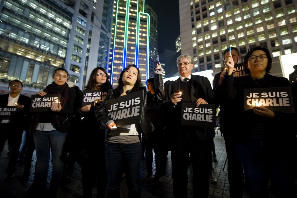 Journalists and other people in Hong Kong hold up pens and hold signs that say "Je suis Charlie" (I am Charlie) during a vigil on January 9.