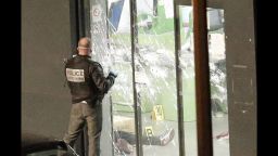 A police officer closes the bullet ridden door next to a body lying in a kosher market in Paris on Friday, January 9.