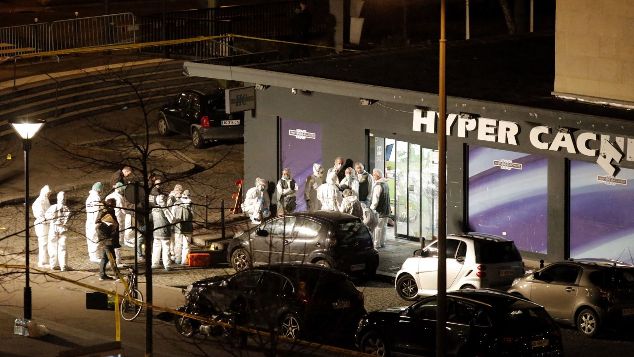 Forensics investigators gather outside the grocery store. French President Francois Hollande said four people were killed.