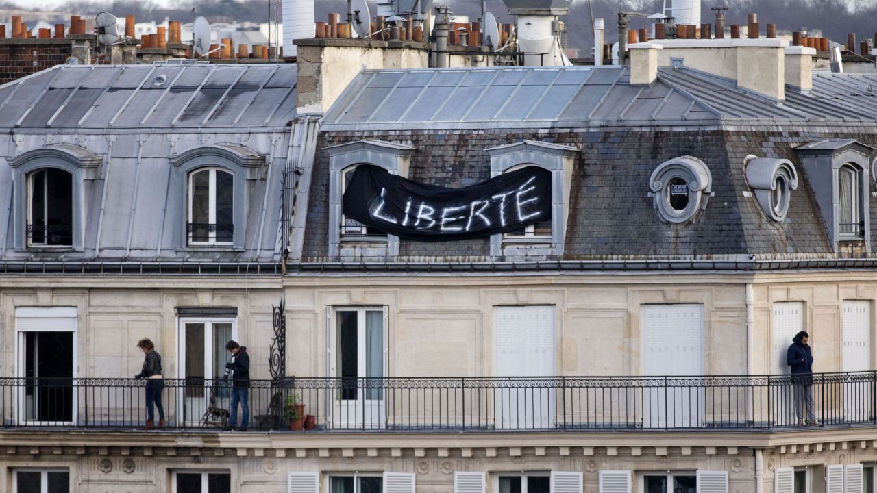 A banner attached to a house overlooking the Place de la Republique reads "Freedom" as thousands of people gather below.
