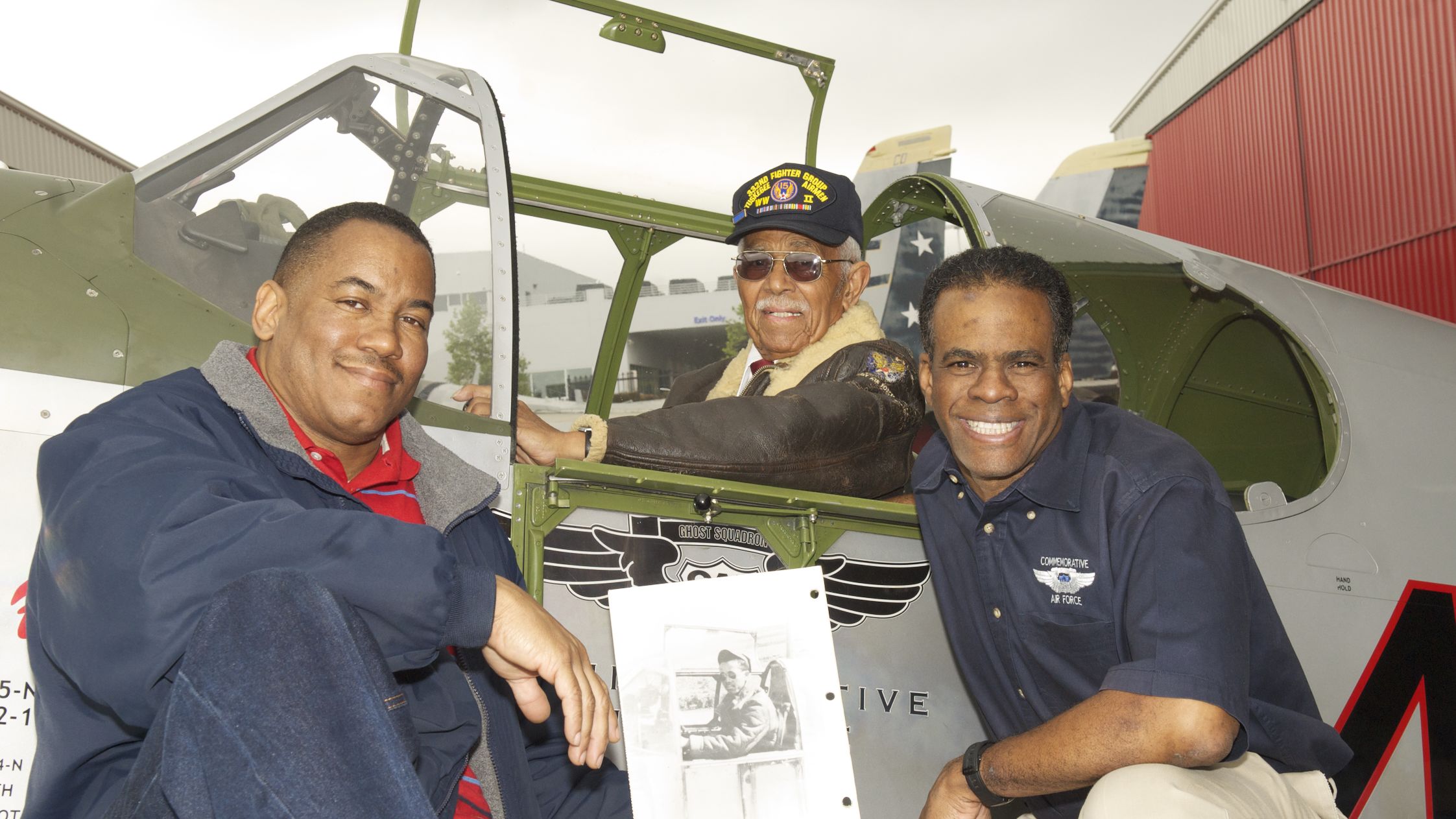 Clarence Huntley Jr., center, poses in the cockpit of a P-51 Mustang with his nephew, Craig Huntly, left, and Brad Lang. Craig Huntly holds a photo of his uncle in 1944.