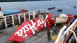 Crew members of Crest Onyx ship prepare to unload parts of AirAsia Flight 8501 from a ship at Kumai port in Pangkalan Bun,Sunday, Jan.11, 2015. A day after the tail of the crashed AirAsia plane was fished out of the Java Sea, the search for the missing black boxes intensified Sunday with more pings heard. (AP Photo/Achmad Ibrahim)