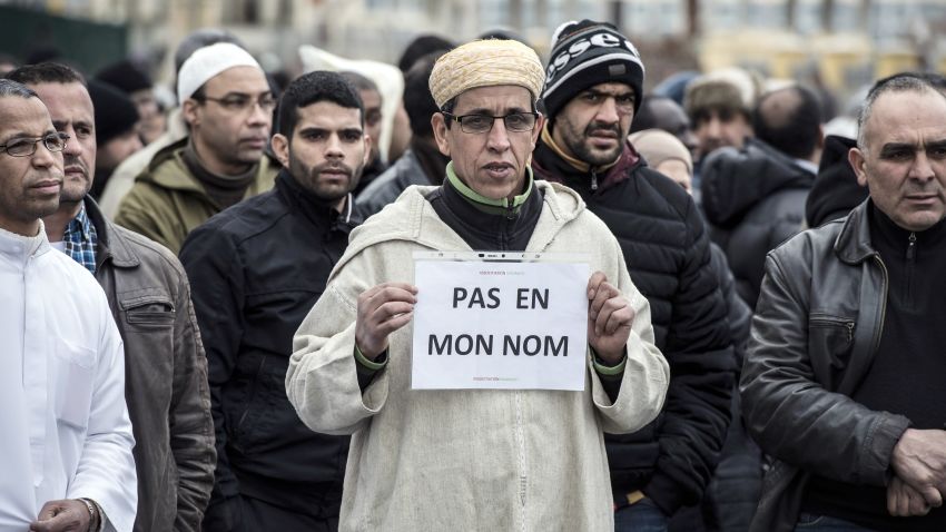A Muslim man holds a placard, reading 'Not in my name', during a gathering on January 9, 2015 near the mosque of Saint-Etienne, eastern France, after the country's bloodiest attack in half a century on the offices of the weekly satirical Charlie Hebdo killing 12 people on January 7.