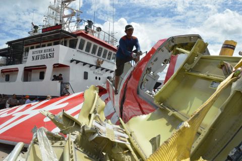 An Indonesian worker cuts part of the plane's tail January 12 after debris from the crash was retrieved from the Java Sea.