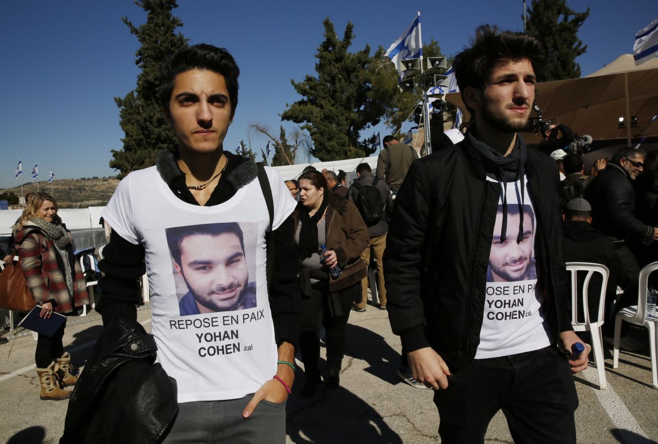 Mourners wearing t-shirts bearing the picture of a victim arrive at Givat Shaul cemetery in Jerusalem.<br />