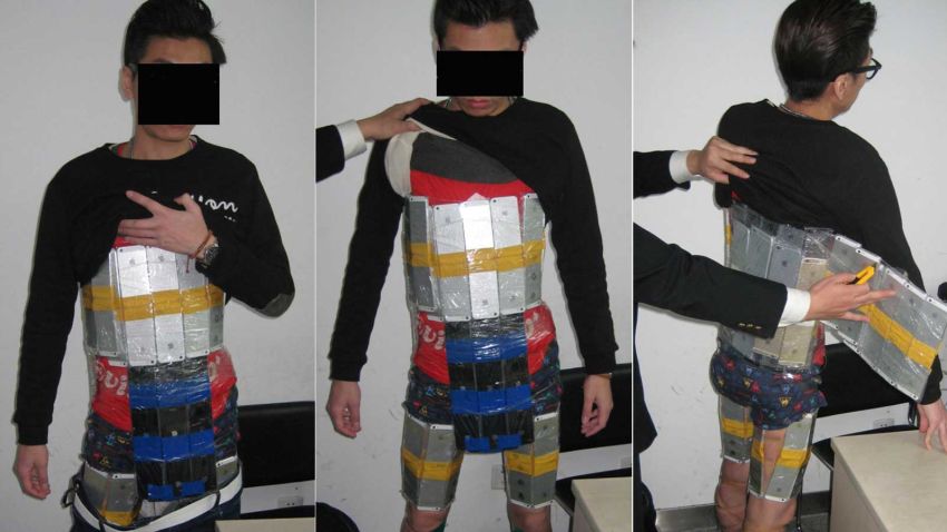 Photos released by customs authorities show dozens of neatly shrink-wrapped shiny iPhones strapped around the man's body.