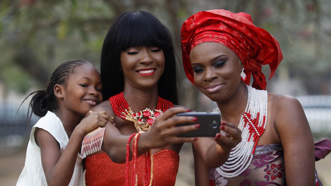 Models in Lagos, Nigeria, take selfies as they display neck beads at a park on Sunday, January 11.