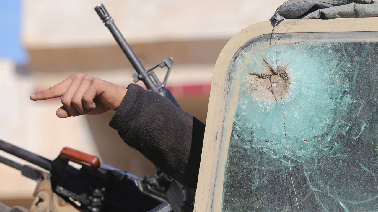 Shiite militia and Iraqi army members point from a bullet-ridden vehicle as they continue to clash with the ISIS militant group Wednesday, January 14, near Baghdad, Iraq.