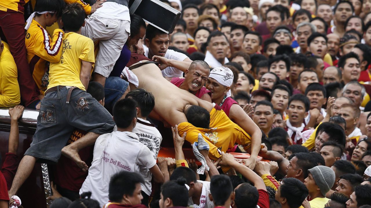 People pull an injured devotee from the carriage of the statue of the Black Nazarene during a religious procession in Manila, Philippines, on Friday, January 9. Hundreds of thousands of Catholics joined the annual procession a week before Pope Francis visited the country.