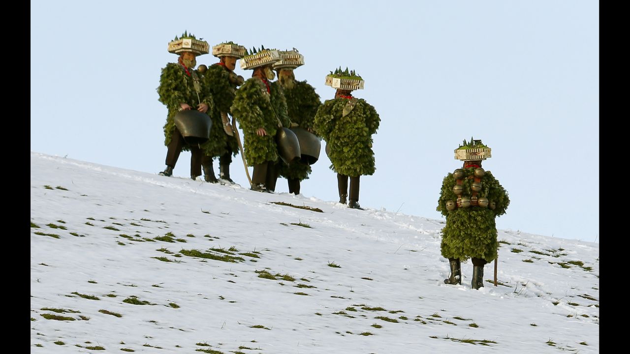 Men dressed as "Chlaeuse," figures that scare away evil spirits, carry bells on a meadow during the traditional Silvesterchlausen festival near Urnaesch, Switzerland, on Tuesday, January 13. Every year on December 31 and January 13, groups of Chlaeuse walk through the countryside of the canton of Appenzell Ausserrhoden.