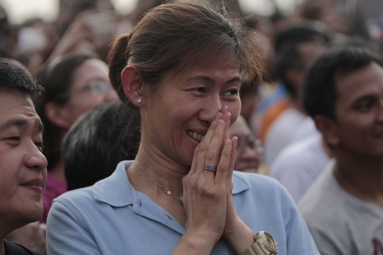 The faithful react while watching a screen showing the arrival of Pope Francis in Manila, on January 15. Giant billboards with an official red and blue "Pope logo" adorn many of Manila's buildings, while curbside vendors sell images of his smiling face on everything from stamps and towels to fans and key chains. 