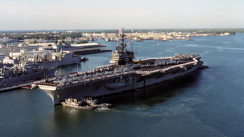 An aerial port side view of Ranger (CV-61), with her Sailors manning the rails and aircraft of Carrier Air Wing 2 (CVW-2) on her deck, as she is nudged into position by harbor tugs Waxahachie (YTB-814), Niantic (YTB-781) and Neodesha (YTB-815), at Naval Station Pearl Harbor, HI, March 8, 1993. US Navy photo by PH3 Bos (DVIC id: DN-SC-05-10867).