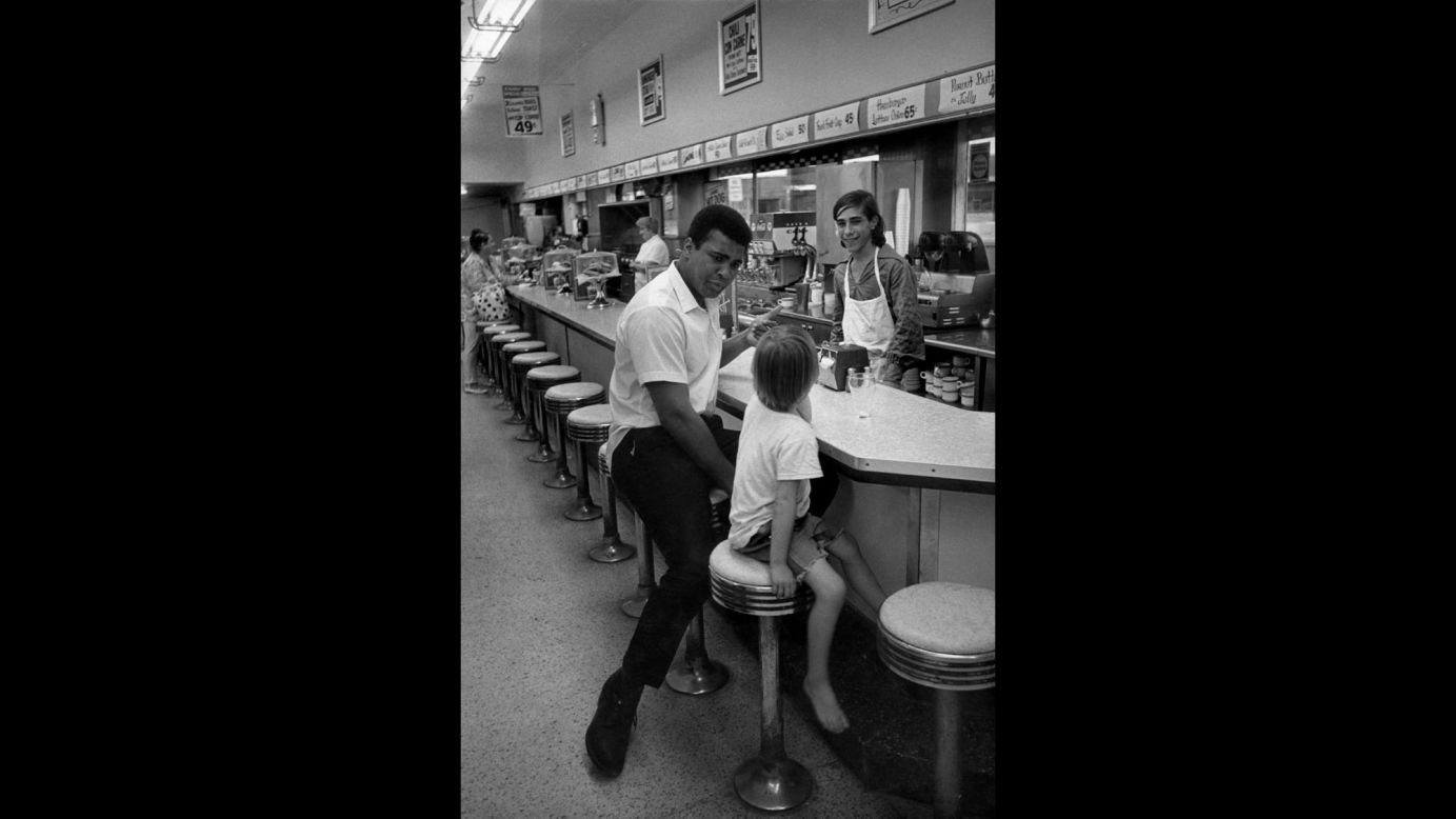 Ali sits with a child at a restaurant counter. 