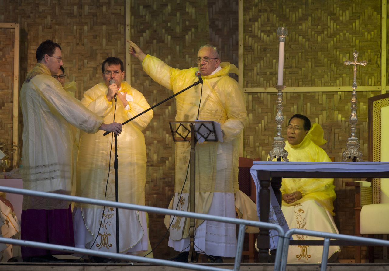 Pope Francis points at the statue of Jesus during his speech as he celebrates a mass in Tacloban, on Saturday, January 17.  A rain-drenched but lively crowd wearing yellow and white raincoats welcomed Pope Francis to the typhoon-ravaged central city of Tacloban, chanting "Papa Francesco, Viva il Papa!" 