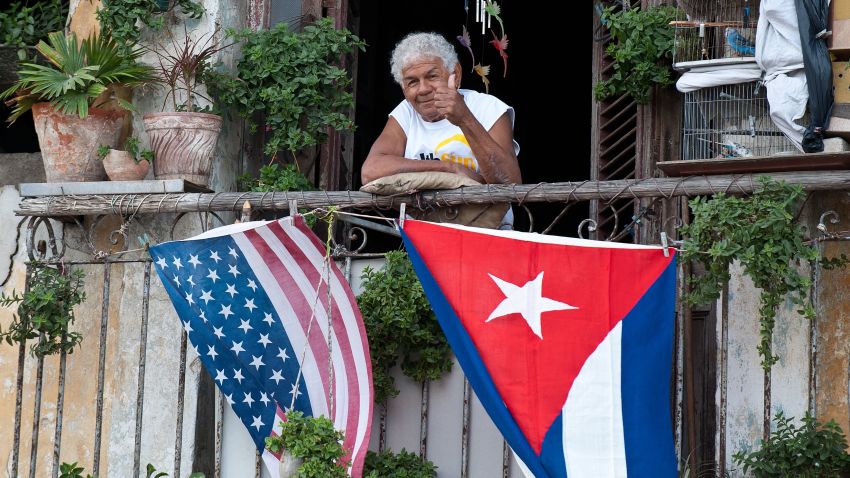 A Cuban gives the thumbs up from his balcony decorated with the US and Cuban flags in Havana, on January 16, 2015. The United States will ease travel and trade restrictions with Cuba on Friday, marking the first concrete steps towards restoring normal ties with the Cold War-era foe since announcing a historic rapprochement. AFP PHOTO/YAMIL Lage (Photo credit should read YAMIL LAGE/AFP/Getty Images)