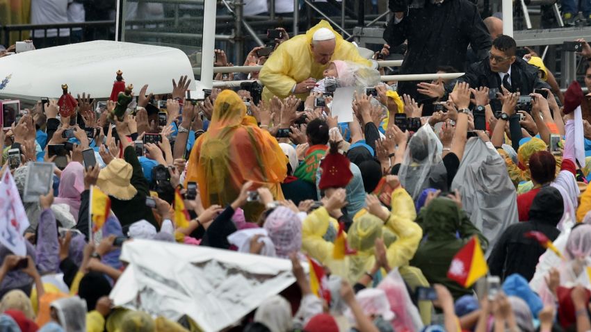 Pope Francis (C) greets people and blesses their religious icons as he arrives to celebrate a mass at a park in Manila on January 18, 2015. Pope Francis celebrated mass with millions of singing and cheering Catholics in the Philippine capital on January 18, in one of the world's biggest outpourings of papal devotion. AFP PHOTO / GIUSEPPE CACACE (Photo credit should read GIUSEPPE CACACE/AFP/Getty Images)