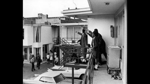 Dr. Ralph Abernathy, Jesse Jackson and others stand on the balcony of the Lorraine Motel in Memphis, Tennessee, on April 4, 1968, pointing in the direction of the gunshots that killed King, who lies at their feet.