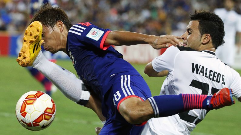 Japan's Takashi Inui, left, is tackled by Iraq's Waleed Salem Al-Lami during an Asian Cup match played Friday, January 16, in Brisbane, Australia. Japan, the defending champions, won 1-0 behind a goal from Keisuke Honda.