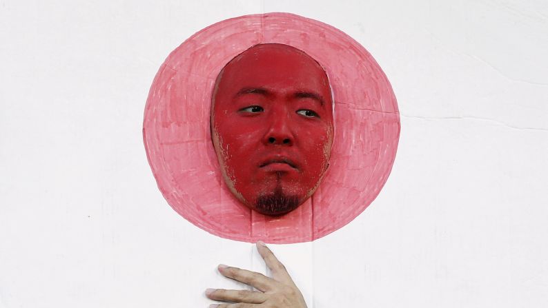 A face-painted Japan supporter sticks his head through a cutout of the Japanese flag before an Asian Cup soccer match on Friday, January 16.