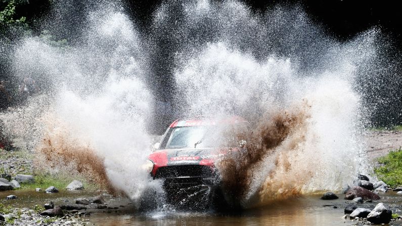 A car driven by Orlando Orly Terranova and Ronnie Graue splashes through muddy water on Thursday, January 15, during the 11th stage of the Dakar Rally. This stage was held in Argentina between the cities of Salta and Termas de Rio Hondo.