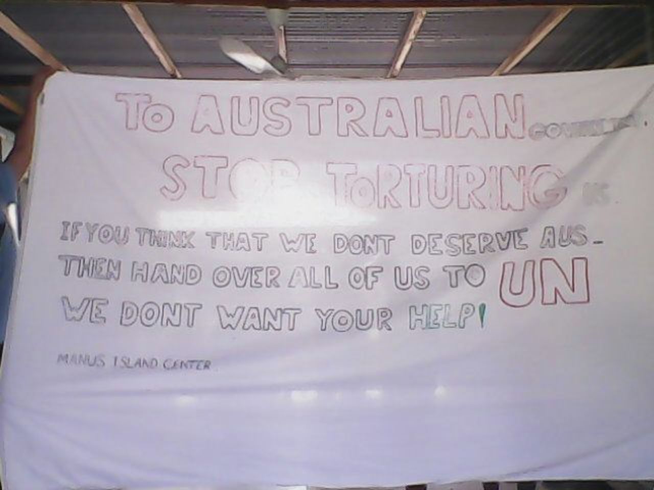 A sign hanging in one of the compounds urges the United Nations to step in. Hundreds of men have been detained at the Australian processing center on Manus Island in Papua New Guinea for 18 months while they wait for their asylum claims to be processed.