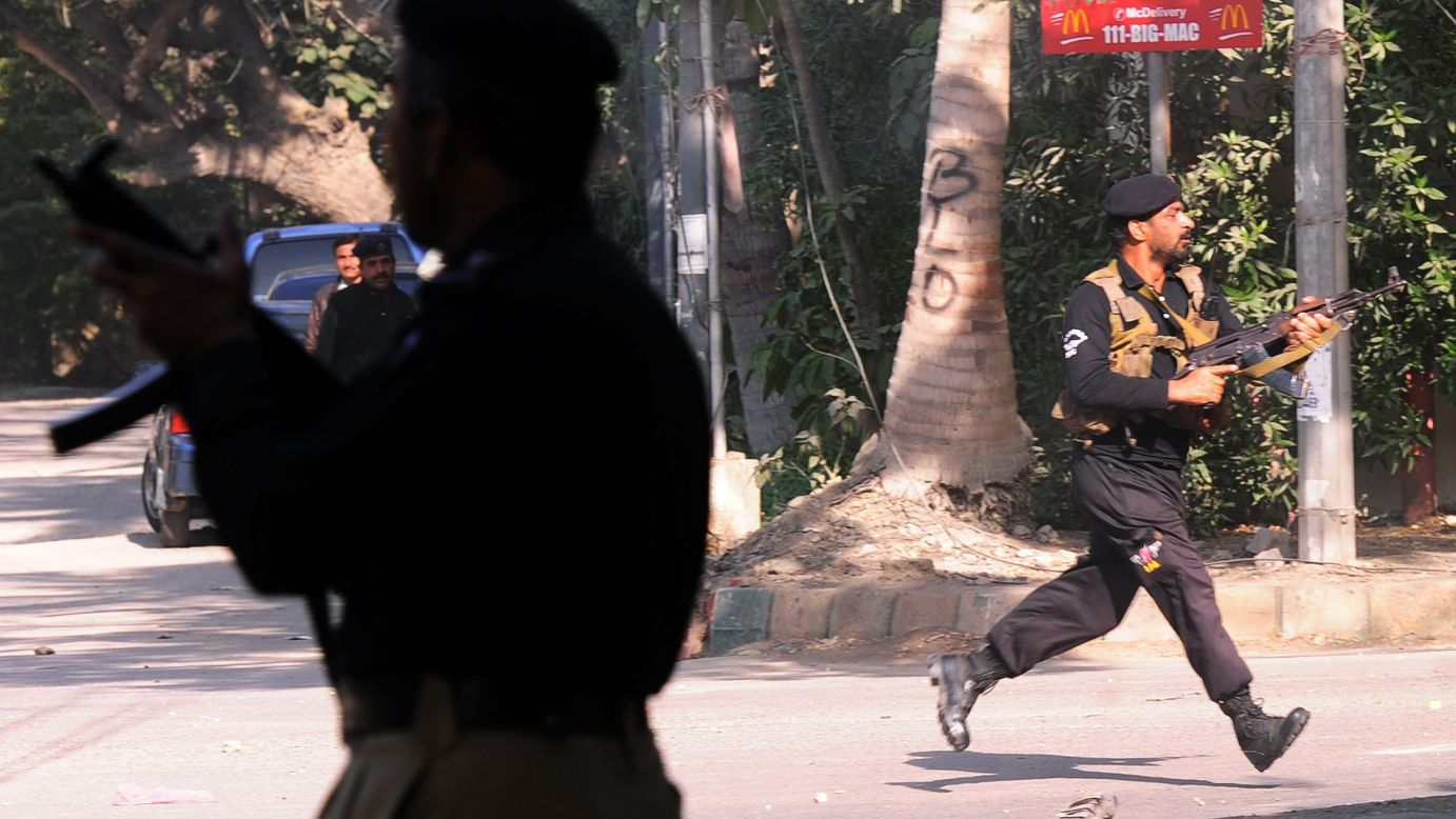 Police officers chase after protesters near the French Consulate in Karachi on January 16.