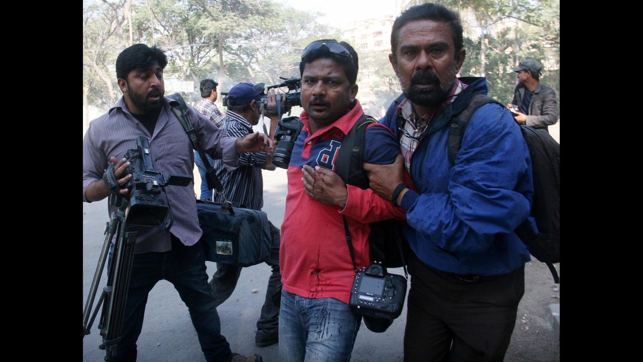 Agence France Presse photographer Asif Hassan, center, is helped after being shot during protests outside the French Consulate in Karachi on January 16.