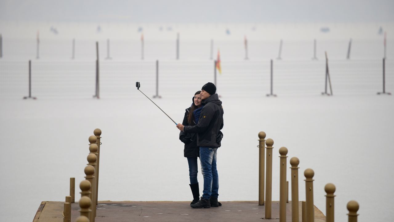 Tourists use a selfie stick as they pose for a photo near Beijing's Kunming Lake on Wednesday, January 14.
