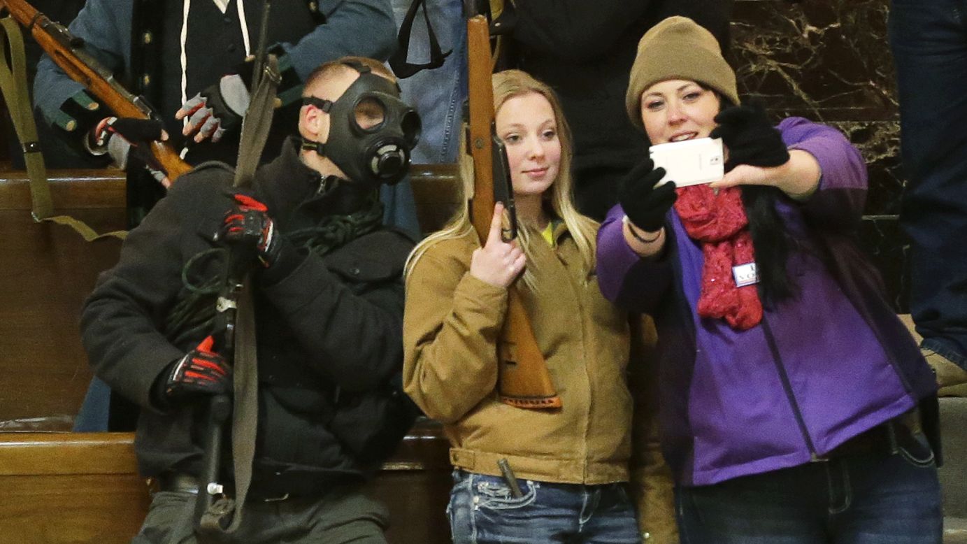 Gun owners pose for a selfie as they display their weapons in the upper gallery of Washington's House chamber Thursday, January 15, in Olympia, Washington. The House was not in session when the photo was taken. Members of the group went to the chamber after a protest outside the legislative building. They protested against Initiative 594, which requires background checks on almost all gun sales and transfers.
