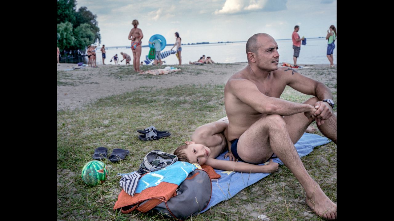 Gyorgg Lakatos sits with his son Sebastain on a beach in Cherkasy by the Kremenchuk Reservoir on the Dnieper River.