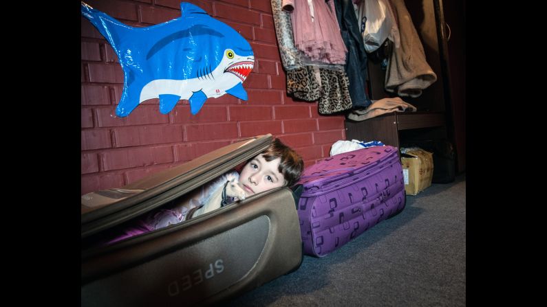 A girl lies in a suitcase her mother and grandmother brought with them while leaving Donetsk.