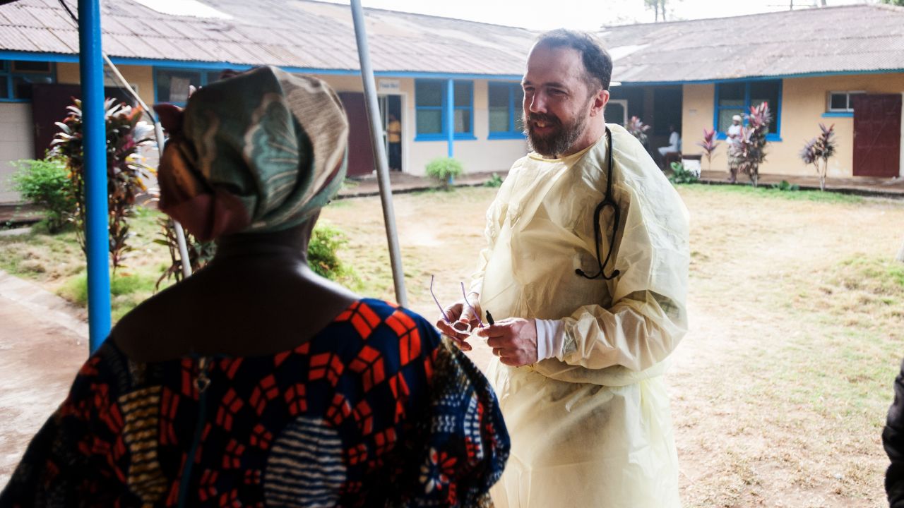 Dr. Rick Sacra visits with a woman at one of the health clinic where he works in Liberia.