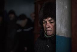 A Ukrainian woman waits for shelling to abate as she shelters inside a building.