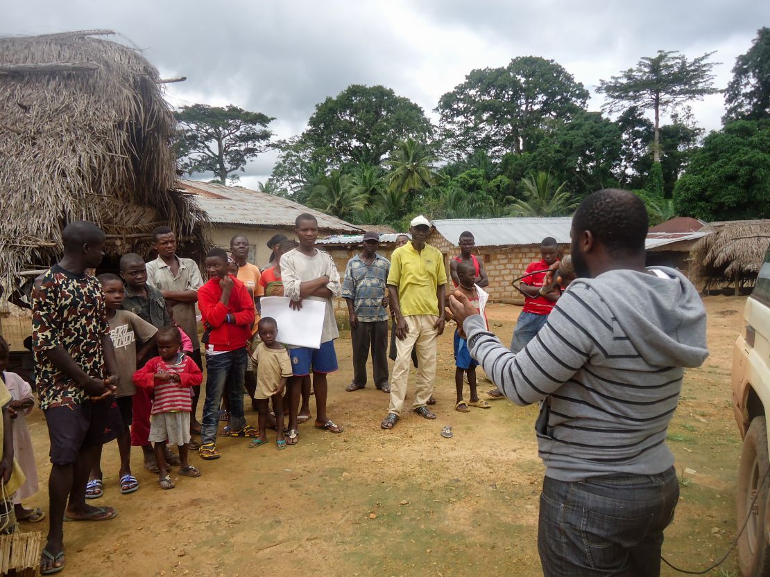 Peace Corps staff meets with members of a local community to educate them about the signs and symptoms of Ebola and steps to take if someone in the community displays symptoms of the virus.  