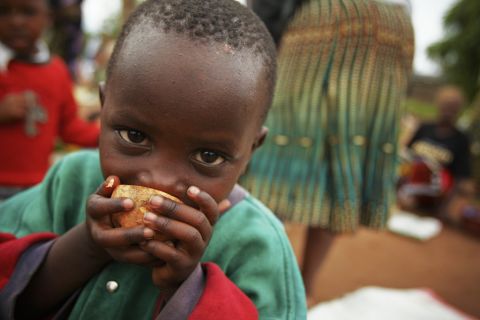 A young boy samples an orange-fleshed sweet potato in a busy market in Mwasonge, Tanzania.