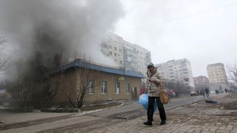 A resident walks by a burning building in Mariupol on Saturday, January 24. 