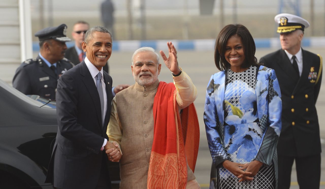 Obama shakes hands with Modi as first lady Michelle Obama stands beside them upon arrival at the Palam Air Force Station in New Delhi.