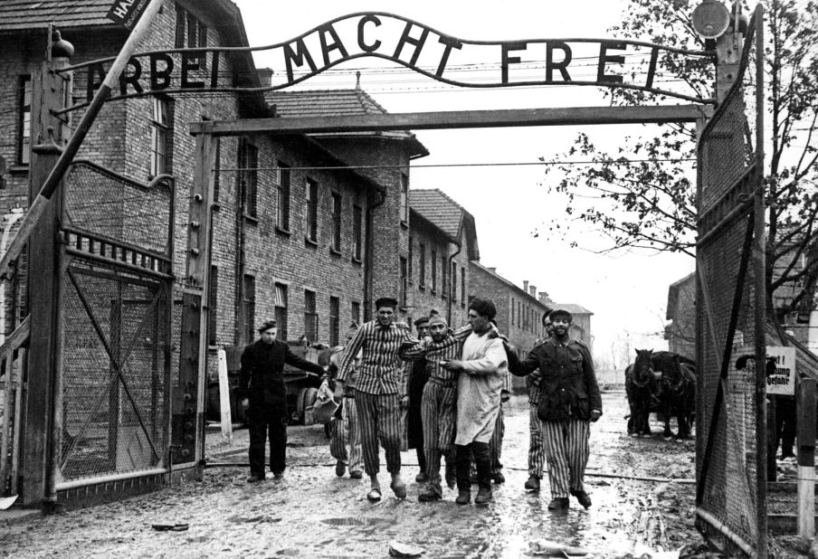 A doctor, center, with  the 322nd Rifle Division of the Red Army, walks with a group of survivors at the entrance to the newly liberated Auschwitz I concentration camp in January 1945. The Red Army liberated the camp on January 27, 1945. Above the gate is the motto "Arbeit macht frei," which translates to "Work sets you free." 