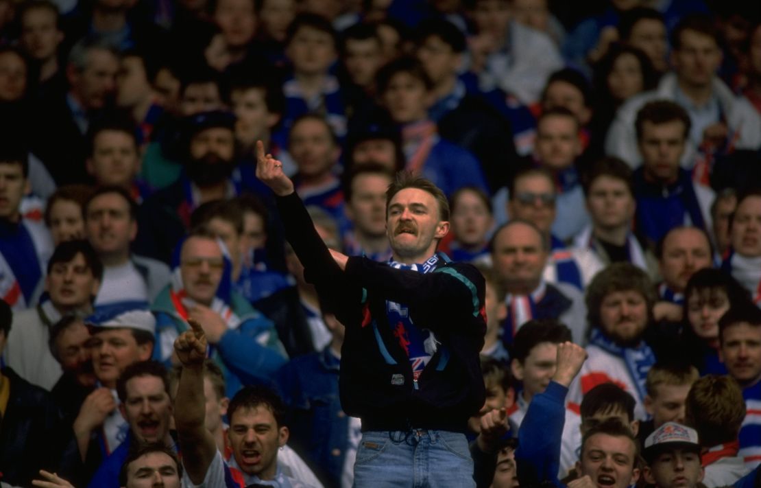 A Rangers fan gestures towards Celtic supporters during an Old Firm game in 1991.